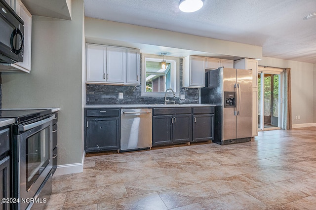 kitchen with stainless steel appliances, sink, backsplash, light tile patterned floors, and a textured ceiling