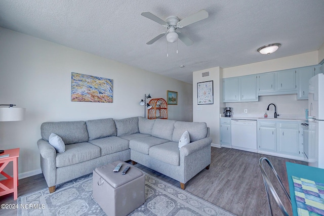 living room with sink, light wood-type flooring, a textured ceiling, and ceiling fan