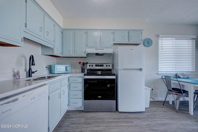 kitchen featuring sink, light wood-type flooring, white appliances, and a textured ceiling