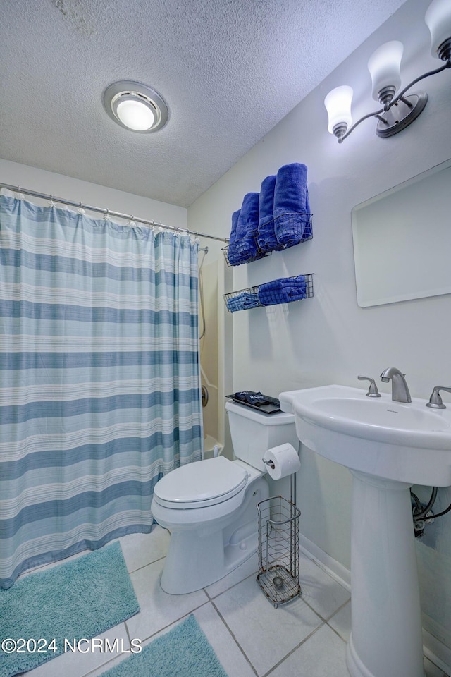 full bathroom featuring toilet, a textured ceiling, sink, shower / bath combination with curtain, and tile patterned floors