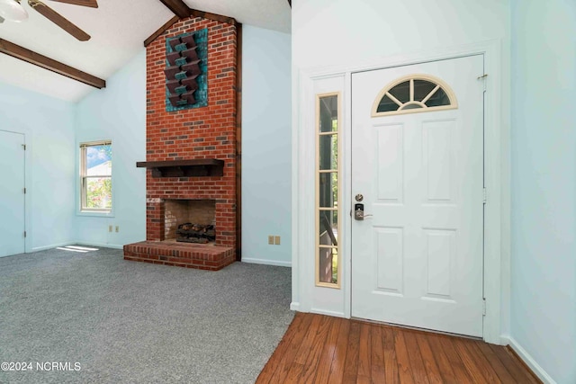 foyer featuring lofted ceiling with beams, ceiling fan, hardwood / wood-style floors, and a fireplace