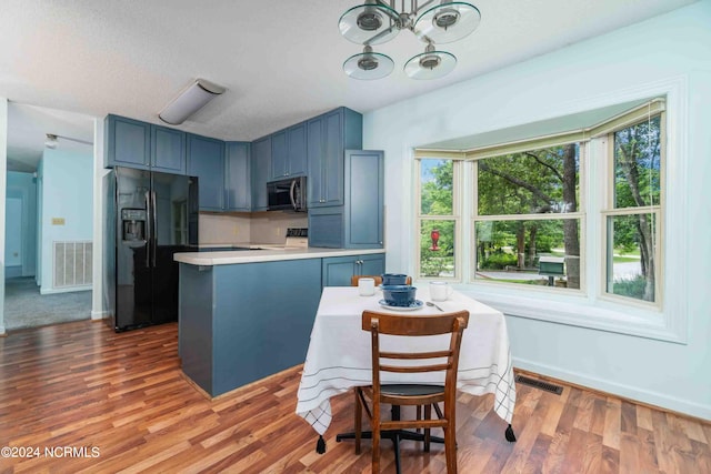 kitchen featuring blue cabinets, wood-type flooring, a textured ceiling, and black fridge with ice dispenser