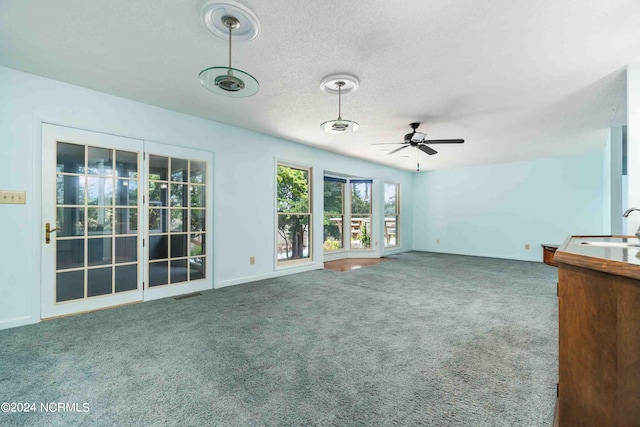 unfurnished living room with ceiling fan, sink, a textured ceiling, and carpet flooring