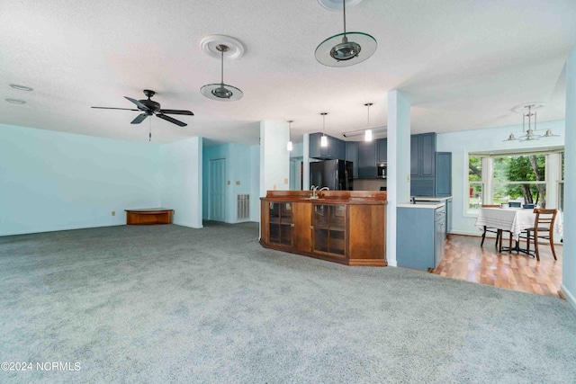 kitchen with black refrigerator, carpet flooring, hanging light fixtures, and a textured ceiling