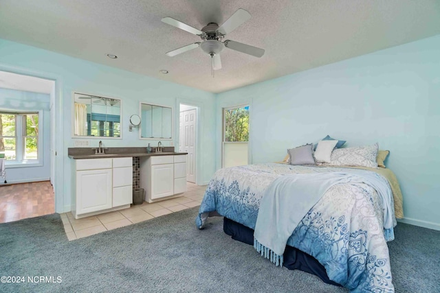 bedroom with ceiling fan, light colored carpet, sink, and a textured ceiling