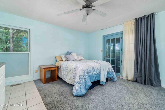 tiled bedroom with ceiling fan and a textured ceiling