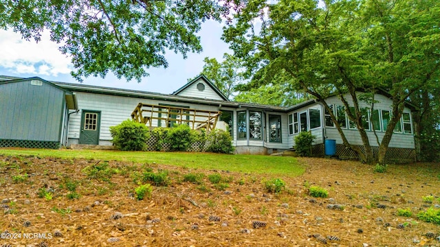 back of property featuring a sunroom and a lawn