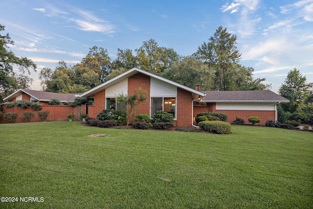 mid-century inspired home featuring brick siding, a chimney, and a front lawn