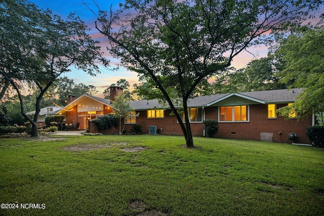 view of front facade featuring central AC, brick siding, crawl space, a lawn, and a chimney