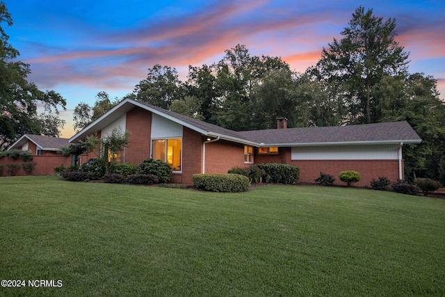 exterior space with brick siding, a chimney, and a lawn