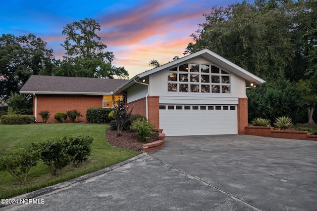 view of front of house with a garage, concrete driveway, brick siding, and a front lawn