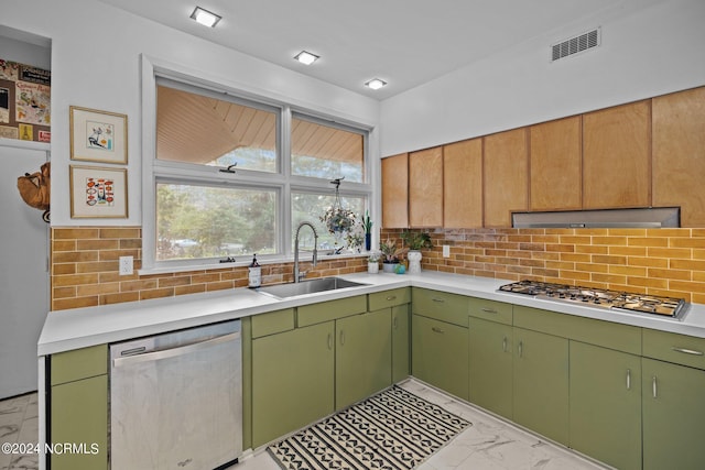 kitchen with a sink, marble finish floor, stainless steel appliances, light countertops, and backsplash