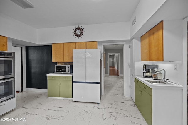 kitchen featuring marble finish floor, stainless steel appliances, light countertops, a sink, and green cabinetry