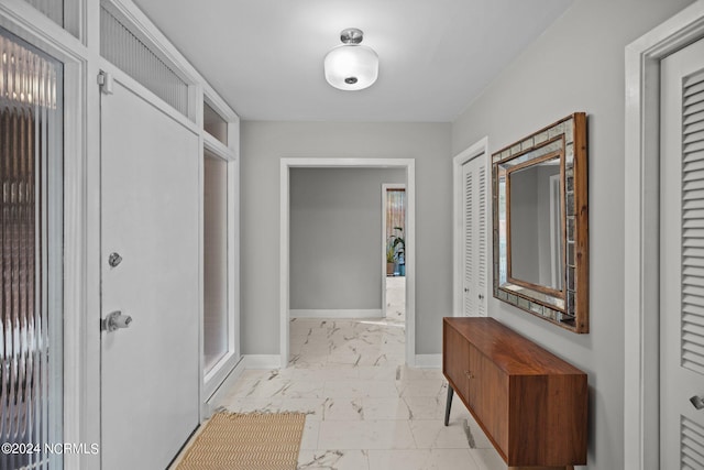 hallway featuring marble finish floor and baseboards