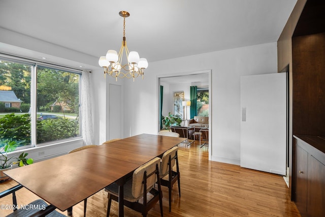 dining area with light wood-style floors and an inviting chandelier