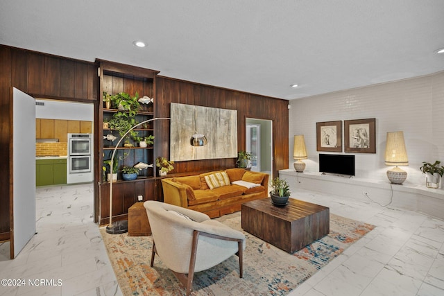 living area featuring recessed lighting, marble finish floor, and wood walls