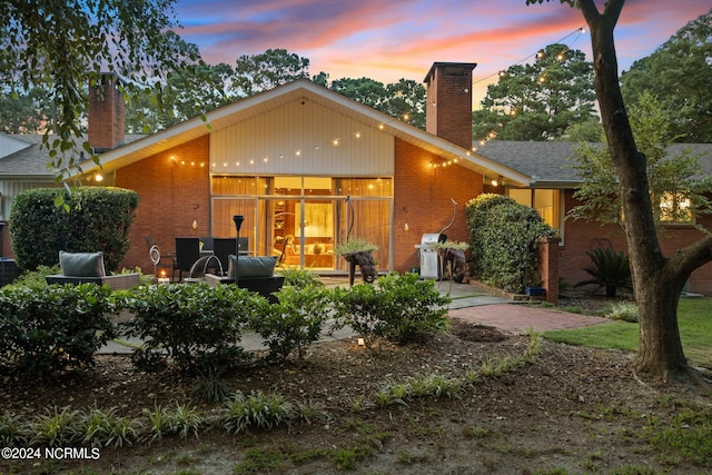 back of property featuring brick siding and a chimney