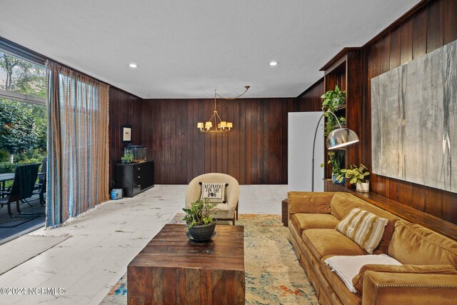 living room featuring marble finish floor, recessed lighting, an inviting chandelier, and wooden walls