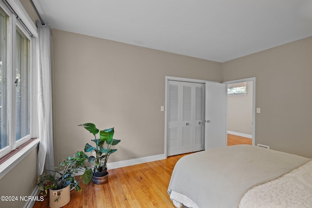 bedroom with a closet, light wood-style flooring, and baseboards