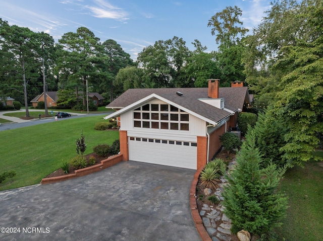 view of front of property with a garage, brick siding, driveway, a chimney, and a front yard