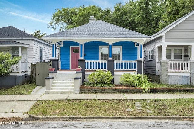 bungalow-style house with a porch, roof with shingles, and a chimney