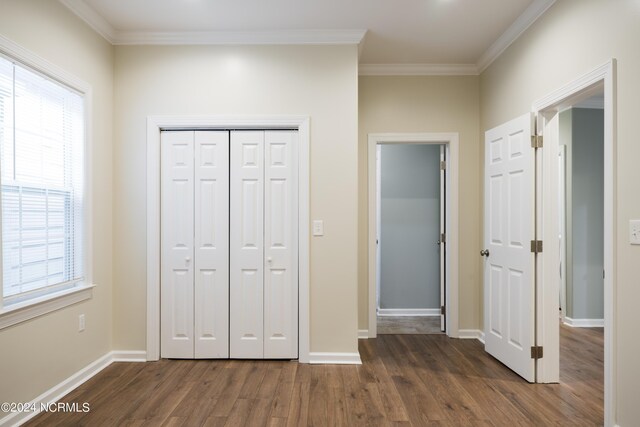 unfurnished bedroom with ornamental molding, multiple windows, and hardwood / wood-style flooring