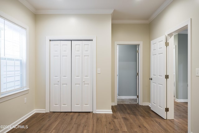 unfurnished bedroom with ornamental molding, a closet, dark wood finished floors, and baseboards