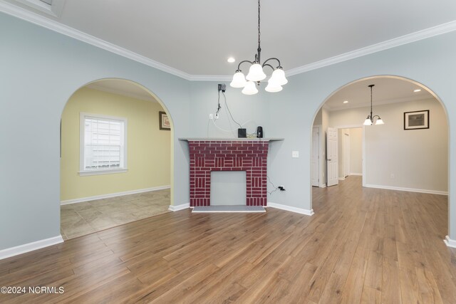 unfurnished living room with crown molding, light wood-type flooring, and an inviting chandelier