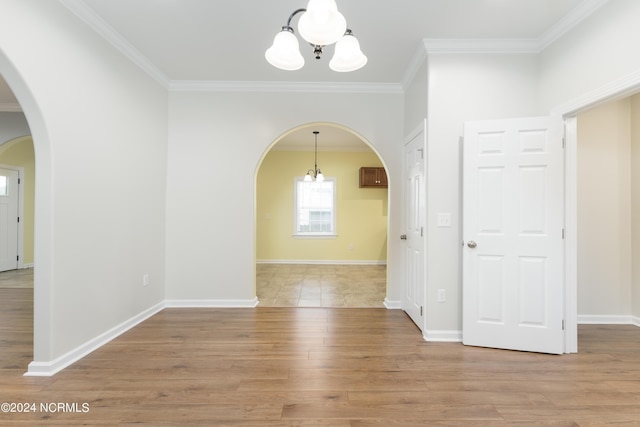 interior space featuring baseboards, arched walkways, wood finished floors, crown molding, and a notable chandelier