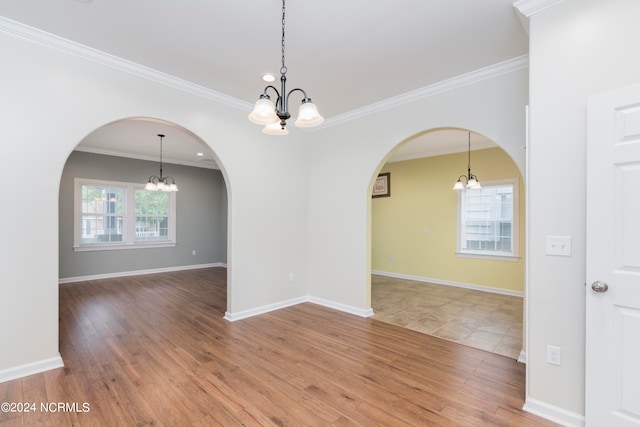 spare room featuring ornamental molding, hardwood / wood-style flooring, and a chandelier