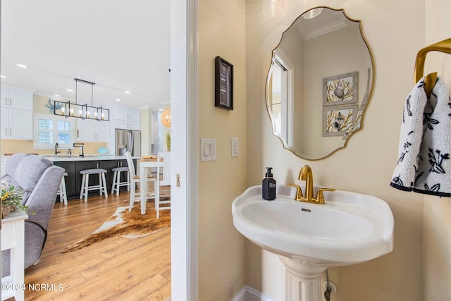 bathroom with crown molding, sink, hardwood / wood-style floors, and a notable chandelier