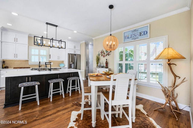 dining area featuring dark hardwood / wood-style flooring, ornamental molding, and an inviting chandelier