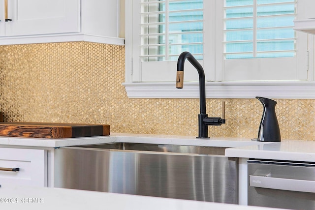 details with white cabinetry, stainless steel dishwasher, sink, and backsplash