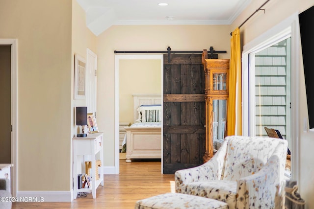 living area with ornamental molding, a barn door, and light wood-type flooring