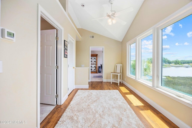 corridor featuring lofted ceiling, light hardwood / wood-style floors, and a healthy amount of sunlight