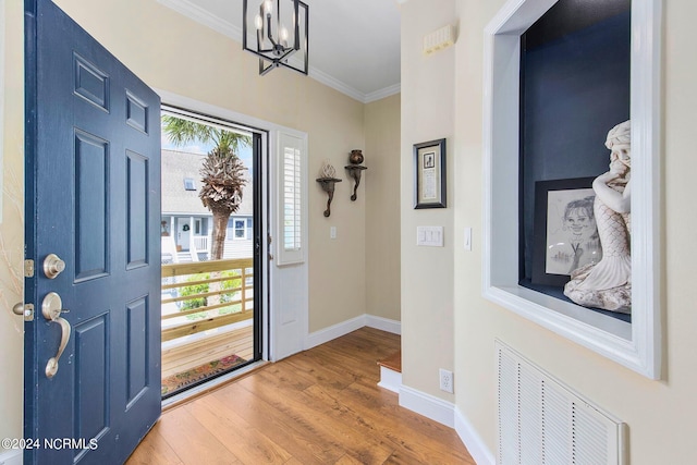 entrance foyer with an inviting chandelier, hardwood / wood-style flooring, and ornamental molding