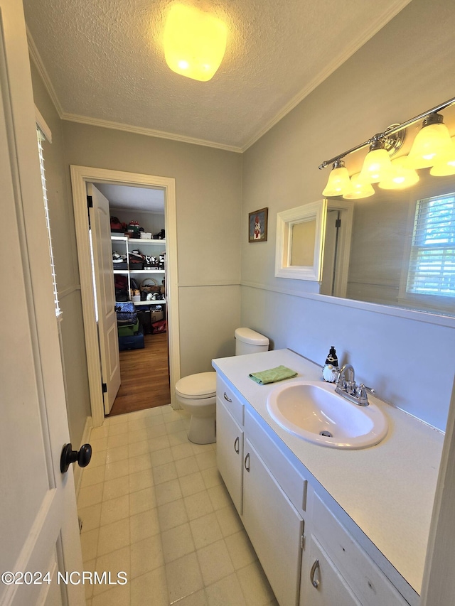 bathroom with vanity, crown molding, toilet, and a textured ceiling