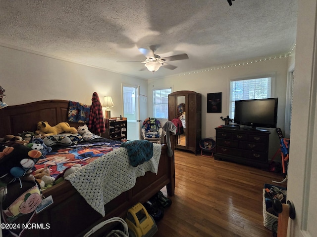 bedroom featuring ceiling fan, wood-type flooring, multiple windows, and a textured ceiling