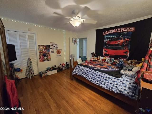 bedroom with ceiling fan, hardwood / wood-style floors, ornamental molding, a textured ceiling, and a closet