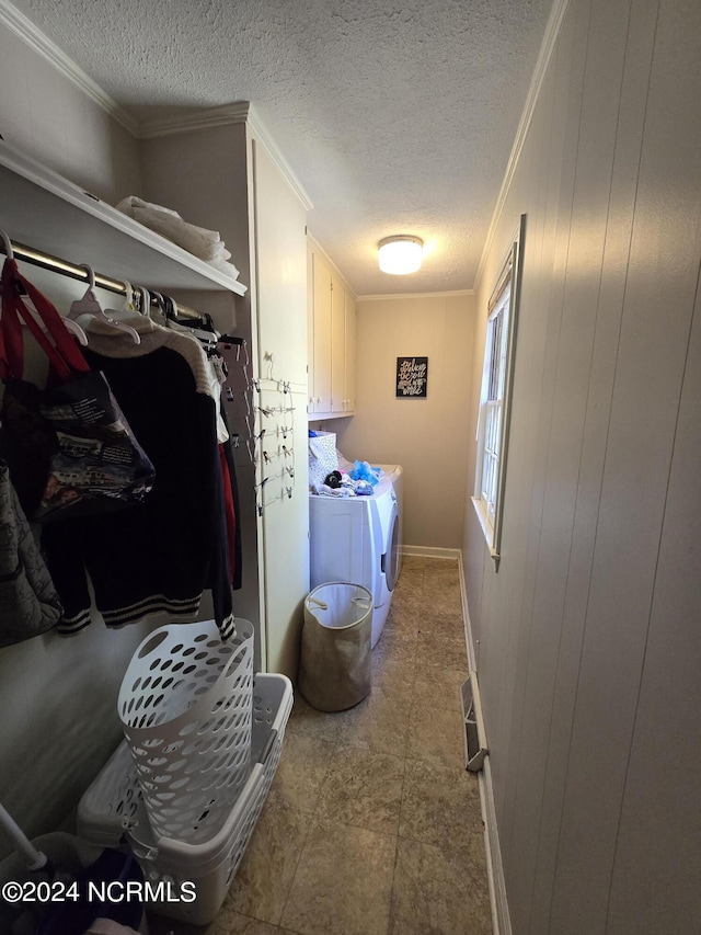 clothes washing area featuring cabinets, ornamental molding, washer and dryer, and a textured ceiling