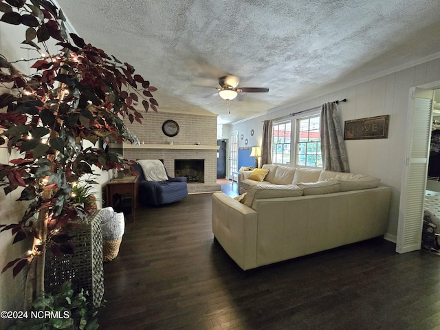 living room featuring dark wood-type flooring, ornamental molding, a brick fireplace, and a textured ceiling