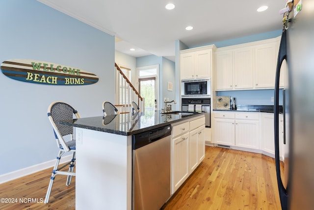 kitchen featuring sink, a kitchen island with sink, black appliances, light hardwood / wood-style floors, and white cabinets