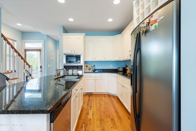 kitchen featuring black appliances, white cabinets, light wood-type flooring, sink, and dark stone countertops