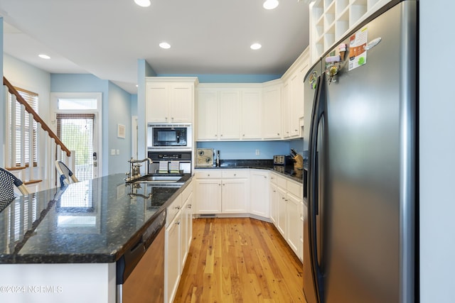 kitchen with white cabinetry, stainless steel appliances, sink, and dark stone countertops