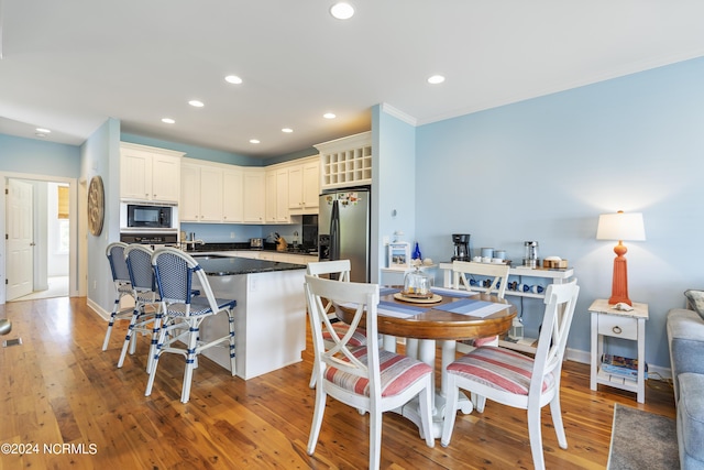 kitchen with black microwave, stainless steel fridge, a kitchen breakfast bar, a kitchen island, and light hardwood / wood-style floors