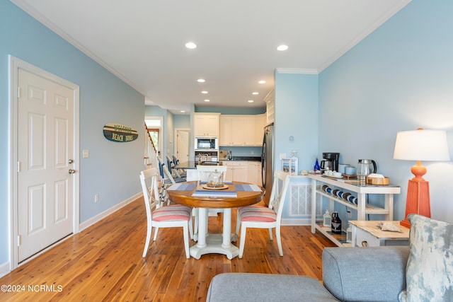 dining space featuring ornamental molding and light hardwood / wood-style floors