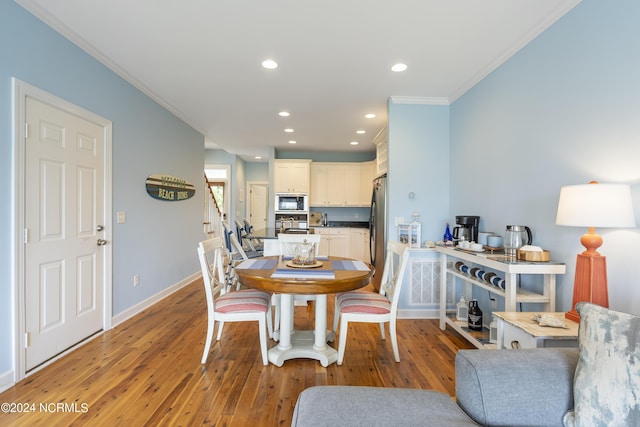 dining room with crown molding and light hardwood / wood-style flooring