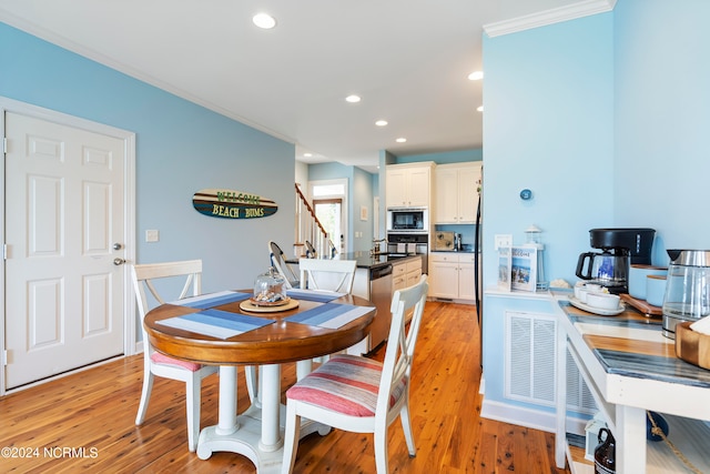 dining area with light hardwood / wood-style flooring and ornamental molding