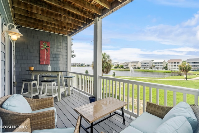 wooden deck featuring a water view, an outdoor hangout area, and a lawn