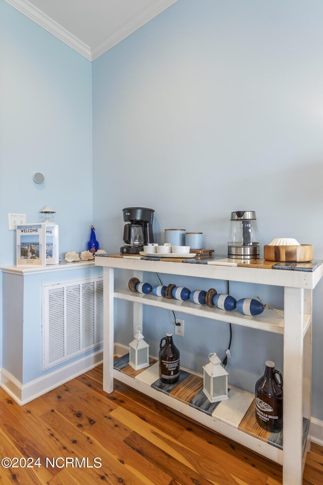 bar with hardwood / wood-style flooring and crown molding